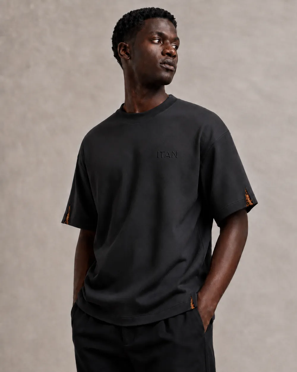 Design concept: black T-shirt, front view, with Ankara inserts at the sleeve vent and hem split.